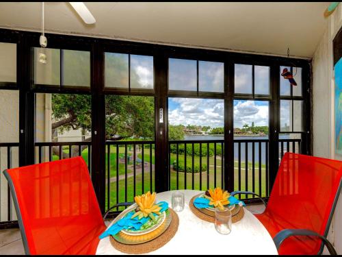 a table with two red chairs and a view of a balcony at Luxury Waterfront Views - Heated Pool - 1400sf Duplex - Minutes to the Beach in Siesta Key