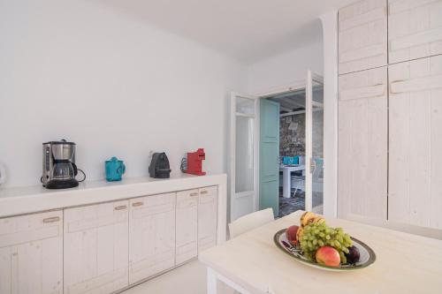a white kitchen with a plate of fruit on a table at Mando Pool Villas w Sea Views - Five Bedrooms in Super Paradise Beach