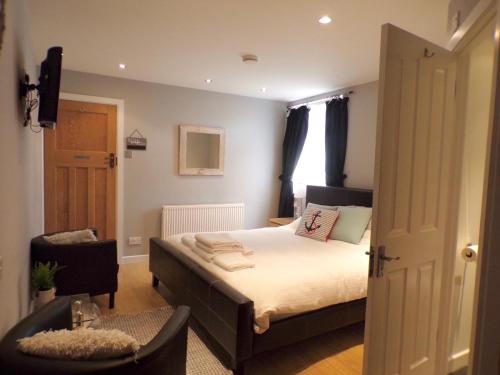 a small bedroom with a bed and a chair at Coast 77 B&B in Poole