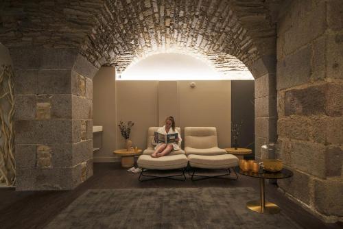 a woman sitting in a chair reading a book at Golden Tulip Saint Malo– Le Grand Bé in Saint Malo