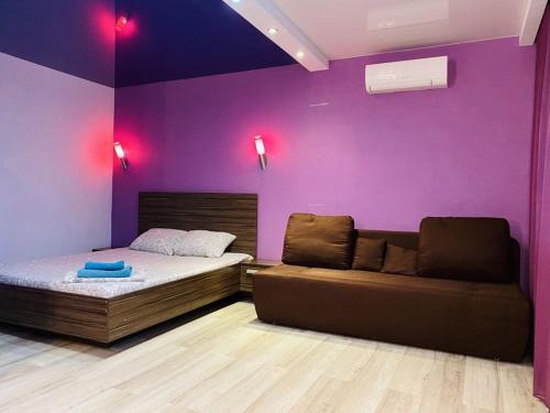 een slaapkamer met paarse muren en een bed en een bank bij LUX на Литейной 17-А in Dnipro