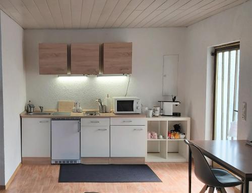a kitchen with white cabinets and a table and a microwave at Apartment zum Wohlfühlen in ruhiger Lage in Pfungstadt