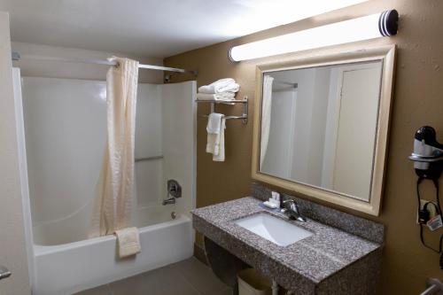 La salle de bains est pourvue d'un lavabo, d'un miroir et d'une baignoire. dans l'établissement Regency Inn, à Monroeville