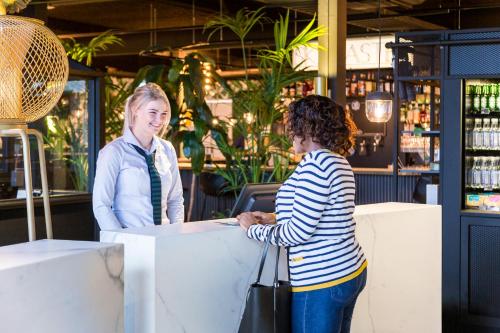 dos mujeres de pie en un mostrador en un bar en ibis Styles Amsterdam Airport, en Schiphol