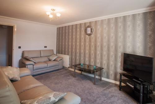- un salon avec un canapé et une télévision dans l'établissement 2 Bed Blackburn Village Apt With Wifi & Parking, à Aberdeen