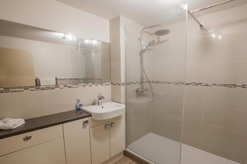 La salle de bains blanche est pourvue d'une douche et d'un lavabo. dans l'établissement 2 Bed Blackburn Village Apt With Wifi & Parking, à Aberdeen