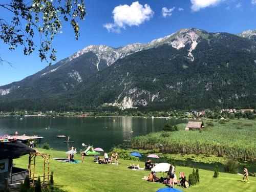 a group of people sitting on the grass near a lake at Haus Seewald in Passriach