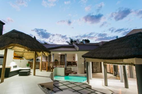 a villa with a swimming pool and two thatch roofs at Stonehill Villa in Bloemfontein