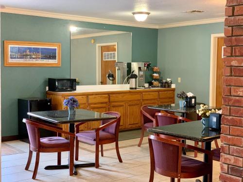 a dining room with two tables and a kitchen at Candlelight Inn & Suites Hwy 69 near McAlester in McAlester