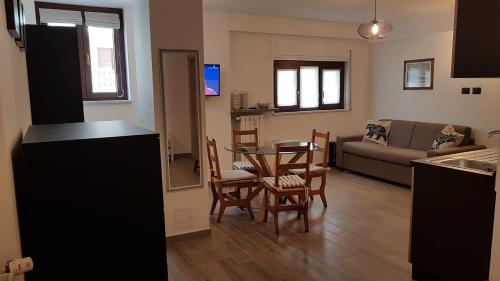 Monolocale Sauze d'Oulx في ساوتسي دو اولكس: مطبخ وغرفة معيشة مع طاولة وكراسي