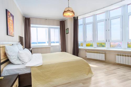 a bedroom with a large bed and windows at ПЕНТХАУС 110 м2 в САМОМ ЦЕНТРЕ ЯРОСЛАВЛЯ in Yaroslavl