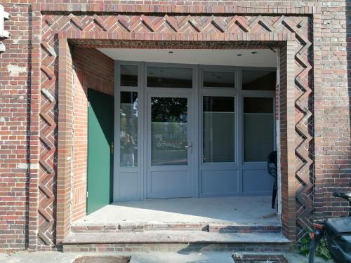 uma entrada para um edifício de tijolos com uma porta azul em Ferienwohnung Seebär em Emden