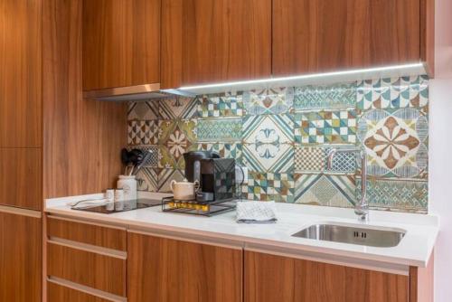 a kitchen with a sink and a tile wall at TMH Torrinha in Porto