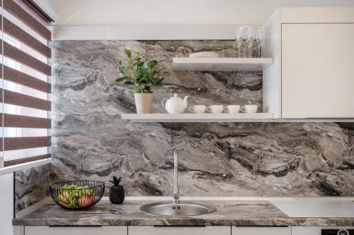 uma cozinha com um lavatório e uma parede em mármore em Million Sunsets Luxury Apartments em St. Paul's Bay