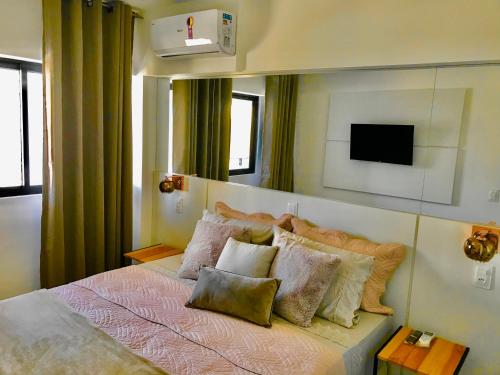 a bedroom with a bed with pillows and a television at Time Apto 410 Quarto Sala Luxo Conforto na Praia Ponta Verde in Maceió