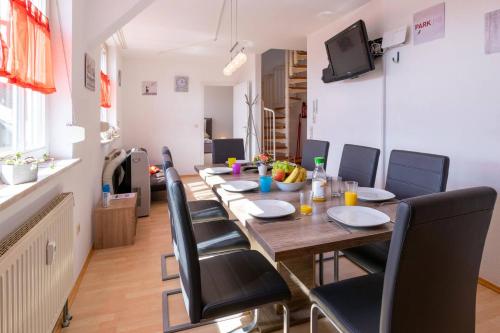 una larga mesa de comedor con sillas y TV en Ferienwohnung Big Family en Ichenhausen