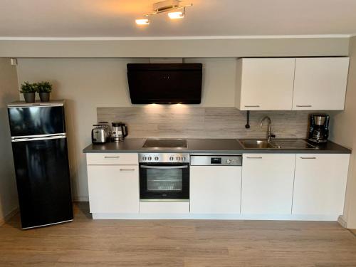 a kitchen with white cabinets and a black refrigerator at Haus am See in Möhnesee