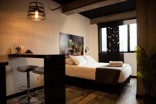 1 dormitorio con cama y mesa con taburete en The Coffee Club, en Manizales