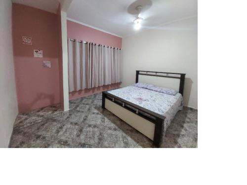 - une chambre avec un lit dans une pièce aux murs roses dans l'établissement Casa de praia Caraguatatuba, à Caraguatatuba