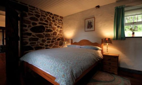 1 dormitorio con cama y pared de piedra en Rosies Cottage, en Maghera