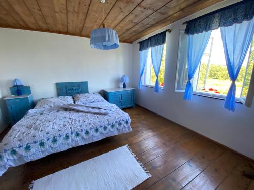 a bedroom with a bed and windows with blue curtains at CHALUPA V PANSKÝM , Staré Křečany u Rumburku in Panský