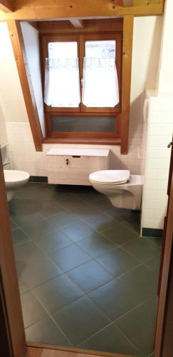 a bathroom with two sinks and a toilet and a window at Ampio appartamento su 2 livelli con garage coperto in Valdaora