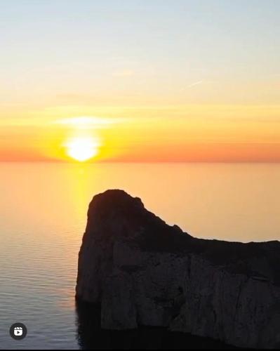 a sunset over the ocean with a rock in the water at Bobo’s Home in Iglesias