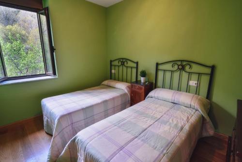 2 camas en una habitación con paredes verdes en Casa Rural El Secreto del Bosque, en La Omañuela