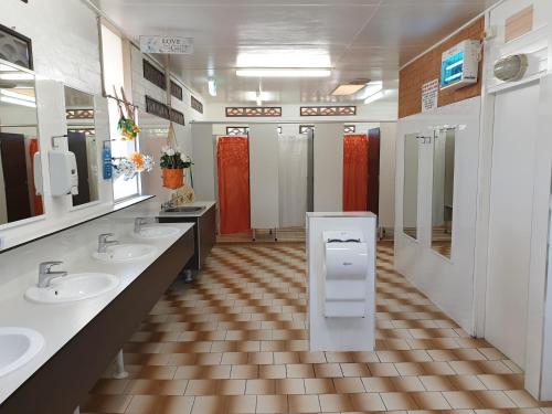 La salle de bains est pourvue de 3 lavabos et de 2 stalles. dans l'établissement Jacaranda Holiday Park, à North Haven