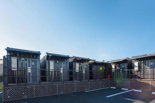 une rangée de maisons modulaires dans un parking dans l'établissement HOTEL R9 The Yard Oyama Tenjin, à Oyama
