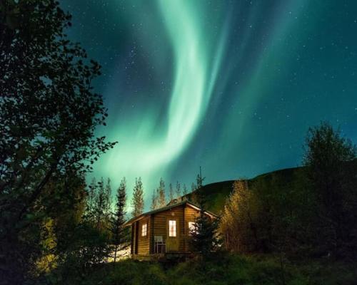 a cabin with the aurora in the sky at night at Arngrimslundur log cabin - cabin 3 in Fludir