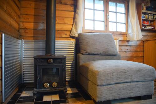 une chambre avec une cuisinière et une chaise dans une cabine dans l'établissement Arngrimslundur log cabin - cabin 3, à Fludir