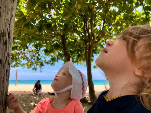 uma mulher segurando um bebê na praia em At Wind Chimes Boutique Hotel em San Juan