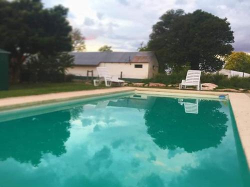 a swimming pool with two chairs and a house at Estancia El Cangue in Porvenir