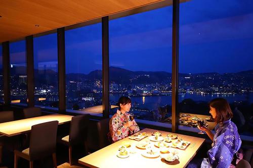 Dos mujeres sentadas en una mesa en un restaurante en Ooedo Onsen Monogatari Nagasaki Hotel Seifu, en Nagasaki