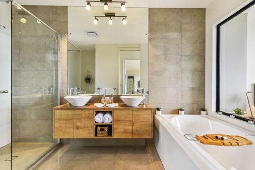 a bathroom with two sinks and a tub and a mirror at The Ridge at Maleny in Maleny