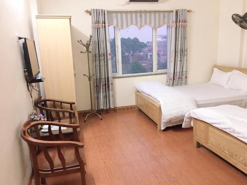 KHÁCH SẠN HÀ ANH 1 NỘI BÀI في Noi Bai: غرفة نوم صغيرة بسريرين ونافذة