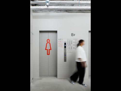 a man walking in front of a bathroom with a toilet sign at 9h nine hours Hakata station in Fukuoka