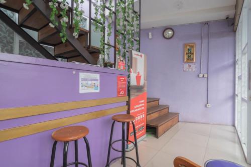Una barra con dos taburetes y una pared morada. en RedDoorz @ Gatot Subroto Street Bandung 3, en Bandung