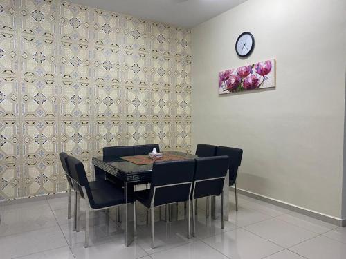 una sala da pranzo con tavolo, sedie e orologio di Homestay ayer keroh mitc a Malacca