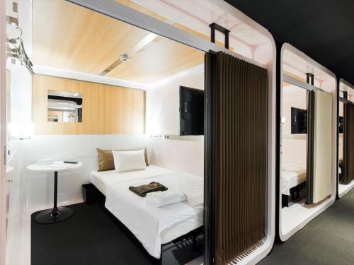 倶知安町にあるトリフィート ホテル＆ポッド ニセコのベッドと小さなテーブル付きの小さな部屋