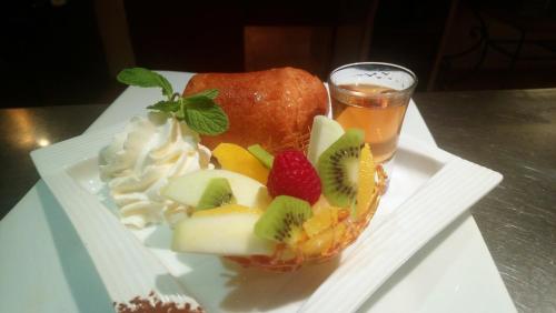 a plate with a fruit dessert and a glass of beer at Logis Le Printemps Hôtel Restaurant - Montélimar in Montélimar