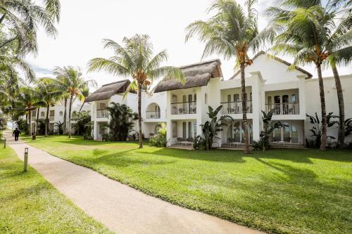 an exterior view of a building with palm trees at Canonnier Beachcomber Golf Resort & Spa in Pointe aux Cannoniers