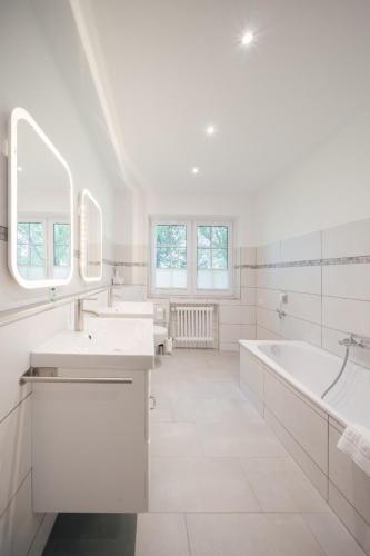 a white bathroom with two sinks and a bath tub at "Reetland" - Haus Hartwig in Tating