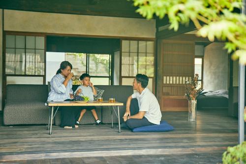 a group of people sitting around a table on a porch at Kominkayado LOOF Okanoie in Yamanashi