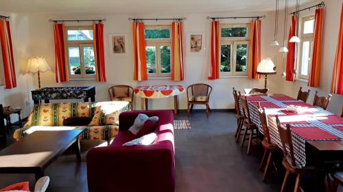 una sala de estar con mesas, sillas y cortinas rojas. en Chalupa Rozálka - ubytování u Adršpachu en Jívka