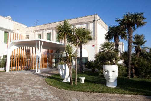 a white building with palm trees in front of it at Arthotel & Park Lecce in Lecce