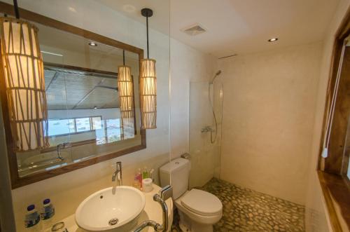 a bathroom with a sink and a toilet and a mirror at Bayview Gardens Hotel in Labuan Bajo