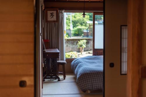 a bedroom with a bed and a desk and a window at Hostel 東風ノ家（Kochi-no-ya） in Aki