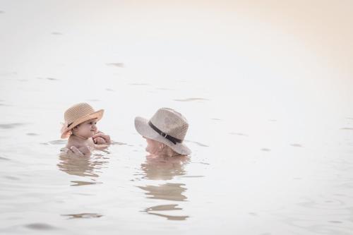 two babies wearing hats sitting in the water at Mauricia Beachcomber Resort & Spa in Grand-Baie